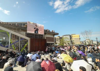 A crowd filling an outdoor festival ground in front of a stage