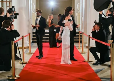 Photographers lining a red carpet as guests arrive at a gala